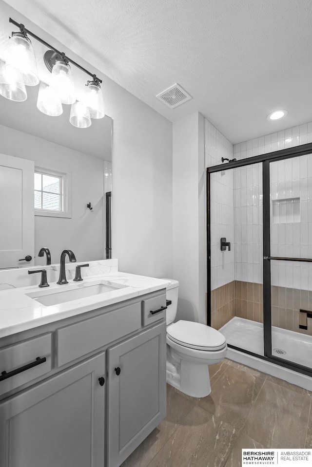 bathroom featuring vanity, toilet, a textured ceiling, and walk in shower