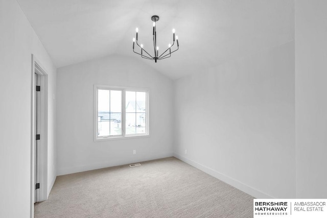 spare room featuring lofted ceiling, light carpet, and a chandelier