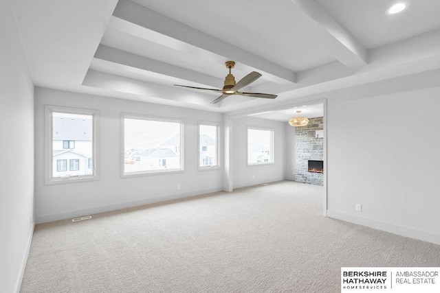 unfurnished living room with a stone fireplace, light carpet, and ceiling fan