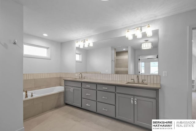 bathroom with tile patterned floors, vanity, ceiling fan, and tiled bath