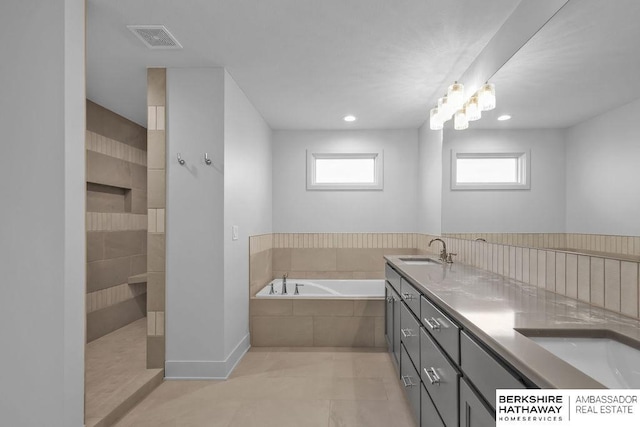 bathroom with tile patterned flooring, vanity, and tiled bath