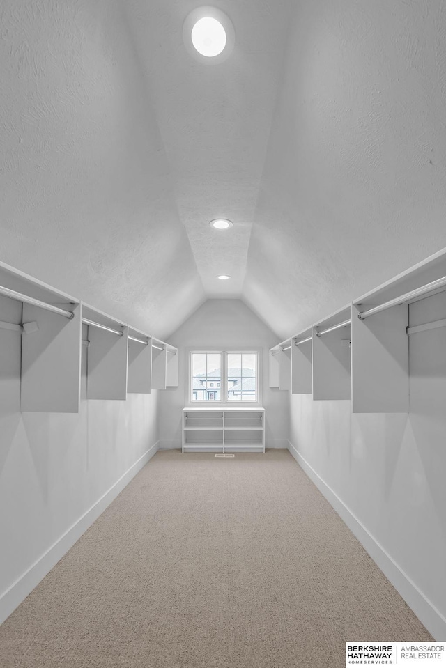 walk in closet featuring carpet flooring and vaulted ceiling