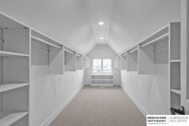 spacious closet with light carpet and vaulted ceiling