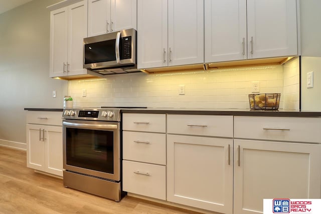 kitchen with stainless steel appliances, light hardwood / wood-style floors, decorative backsplash, and white cabinetry