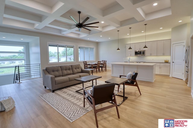 living room featuring beamed ceiling, light hardwood / wood-style floors, ceiling fan, and coffered ceiling