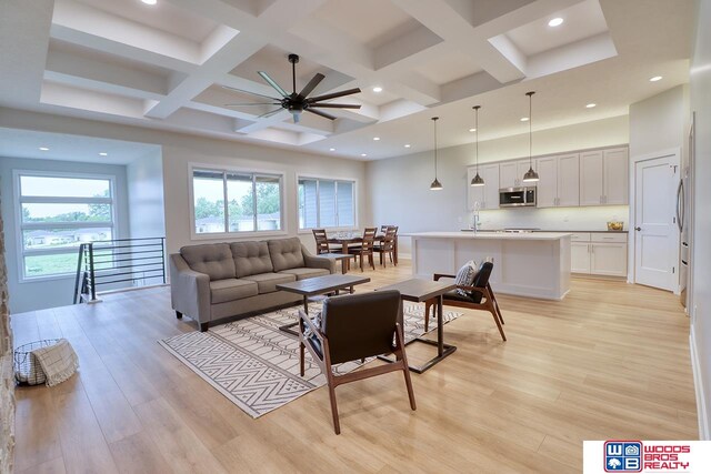 living room featuring light wood-type flooring, beamed ceiling, coffered ceiling, and ceiling fan