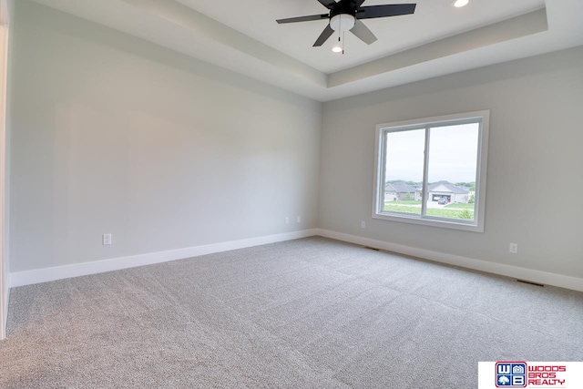 spare room with light carpet, ceiling fan, and a raised ceiling