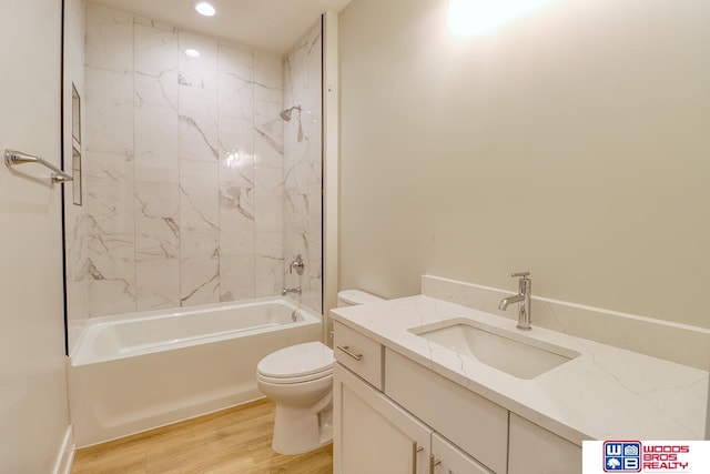 full bathroom with wood-type flooring, vanity, tiled shower / bath combo, and toilet