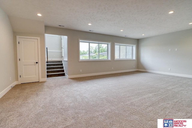 empty room with light carpet and a textured ceiling