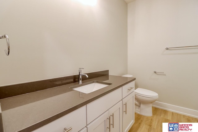 bathroom featuring wood-type flooring, vanity, and toilet