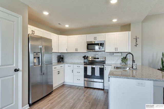 kitchen with white cabinets, appliances with stainless steel finishes, sink, and light hardwood / wood-style flooring