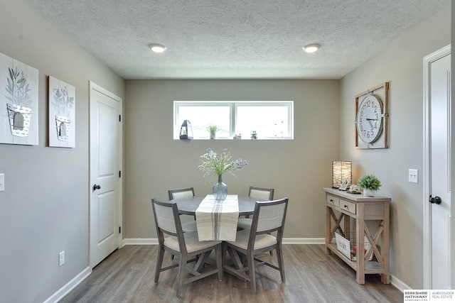 dining area featuring wood-type flooring and a textured ceiling