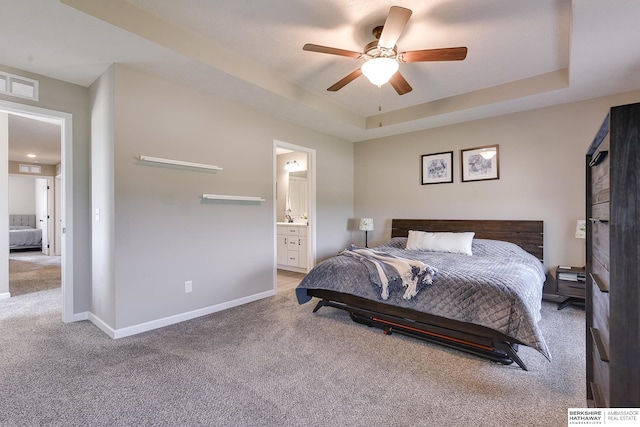 carpeted bedroom featuring ensuite bath, ceiling fan, and a raised ceiling