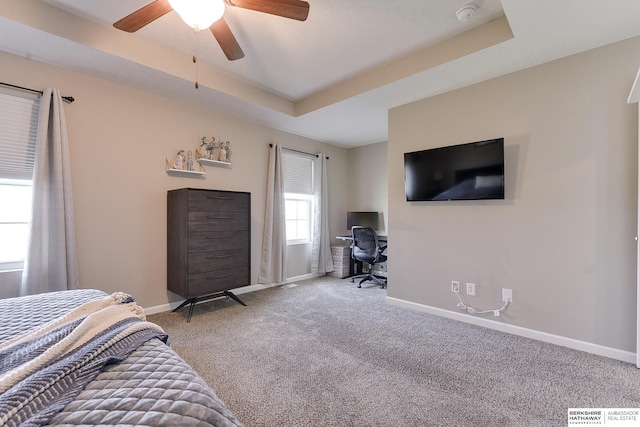 carpeted bedroom featuring ceiling fan and a raised ceiling