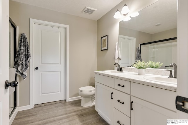 bathroom with vanity, toilet, hardwood / wood-style floors, and an enclosed shower