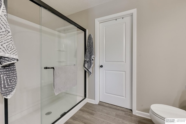 bathroom featuring hardwood / wood-style flooring, toilet, and a shower with door