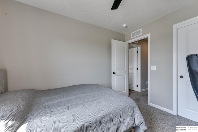 bedroom with a textured ceiling, dark colored carpet, and ceiling fan