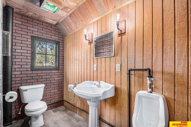 bathroom with wood walls, vaulted ceiling, toilet, and brick wall