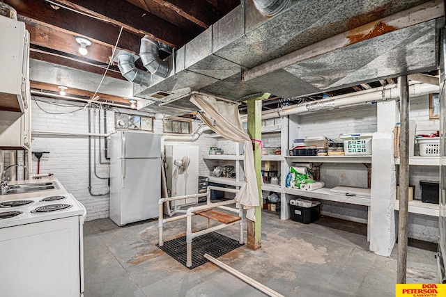 basement featuring white refrigerator, brick wall, and sink