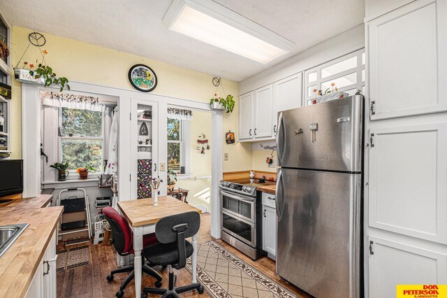 kitchen with stainless steel appliances, white cabinetry, butcher block counters, and dark wood-type flooring