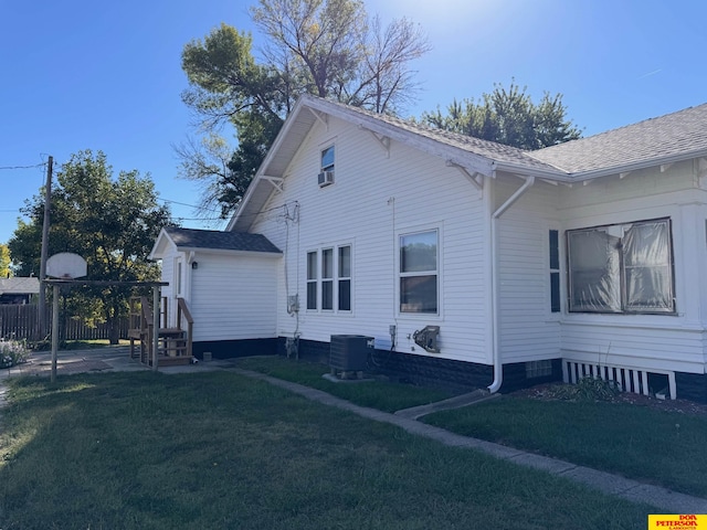 view of side of home with central AC unit and a yard