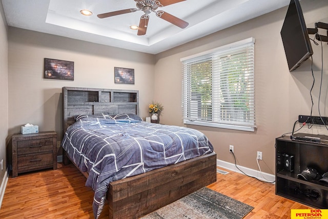 bedroom featuring a tray ceiling, ceiling fan, and hardwood / wood-style flooring