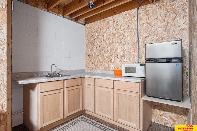 kitchen with stainless steel refrigerator, light brown cabinetry, and sink