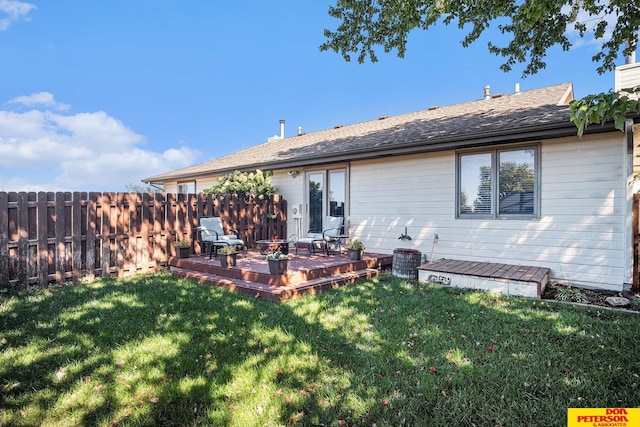 rear view of house featuring a lawn and a deck