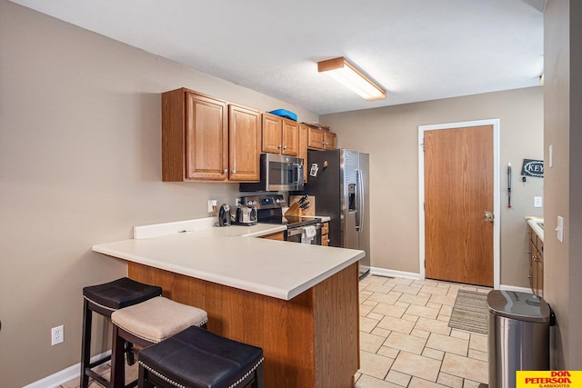 kitchen featuring appliances with stainless steel finishes, kitchen peninsula, and a breakfast bar