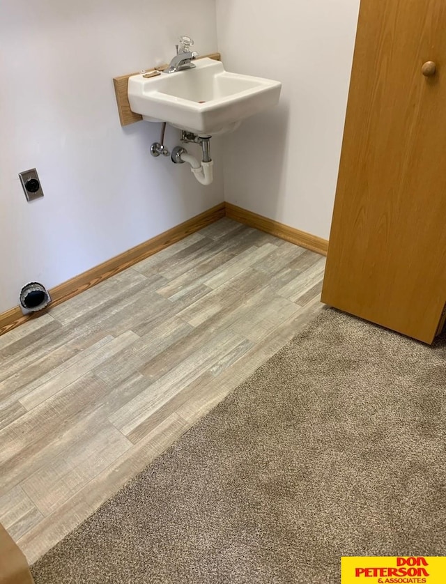 interior space featuring electric dryer hookup, sink, and hardwood / wood-style flooring