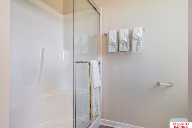 bathroom featuring a shower with shower door and toilet