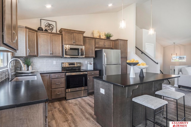 kitchen featuring sink, a center island, vaulted ceiling, and appliances with stainless steel finishes