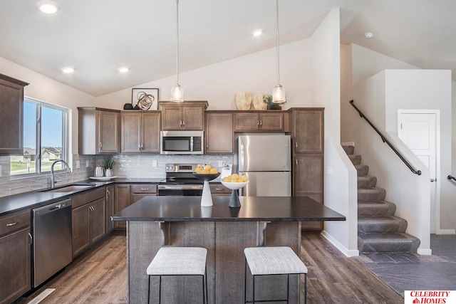 kitchen featuring hanging light fixtures, stainless steel appliances, a kitchen island, a kitchen breakfast bar, and sink