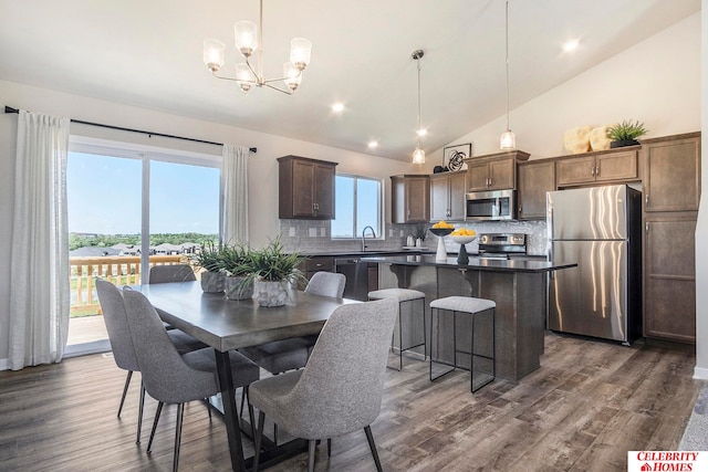 dining area with sink, high vaulted ceiling, an inviting chandelier, and dark hardwood / wood-style floors