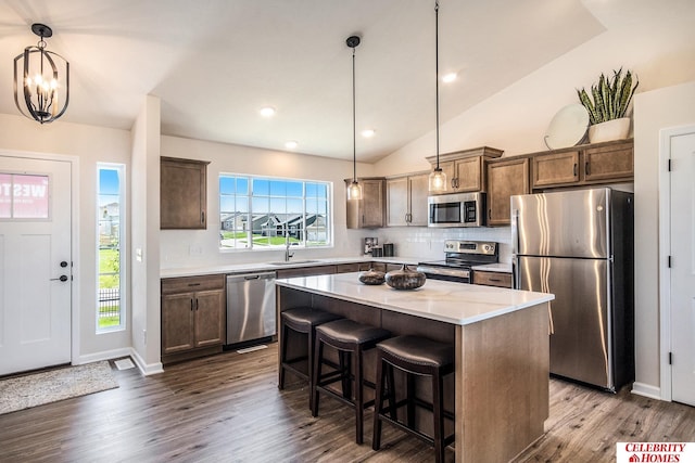 kitchen with appliances with stainless steel finishes, a kitchen island, pendant lighting, and a wealth of natural light