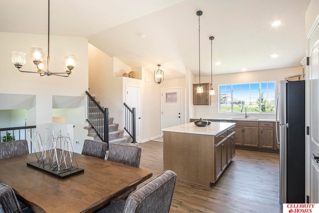 dining room featuring an inviting chandelier, vaulted ceiling, hardwood / wood-style flooring, and sink