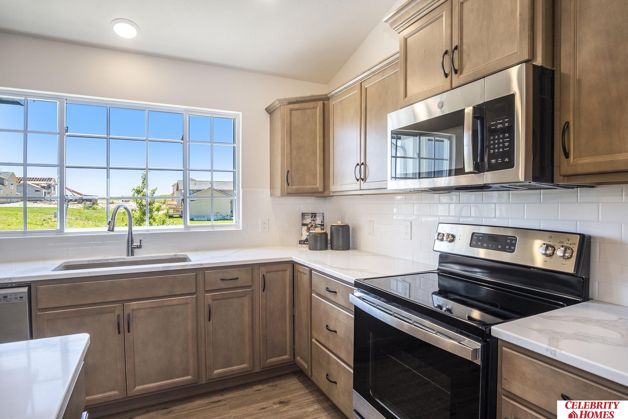 kitchen featuring sink, tasteful backsplash, light hardwood / wood-style flooring, appliances with stainless steel finishes, and vaulted ceiling