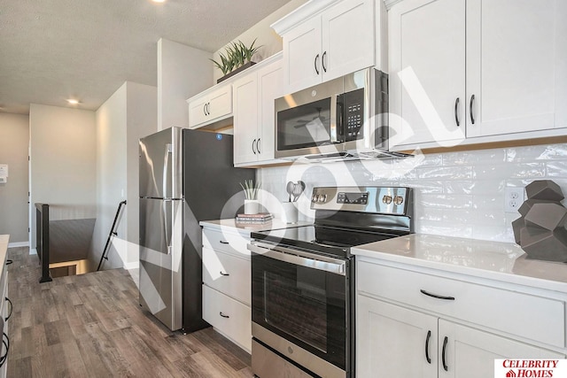 kitchen featuring decorative backsplash, white cabinetry, wood finished floors, and stainless steel appliances
