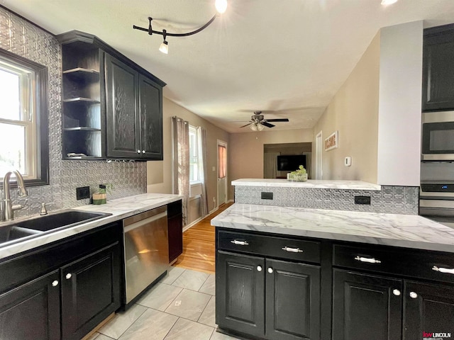 kitchen featuring ceiling fan, sink, light hardwood / wood-style flooring, stainless steel appliances, and light stone countertops