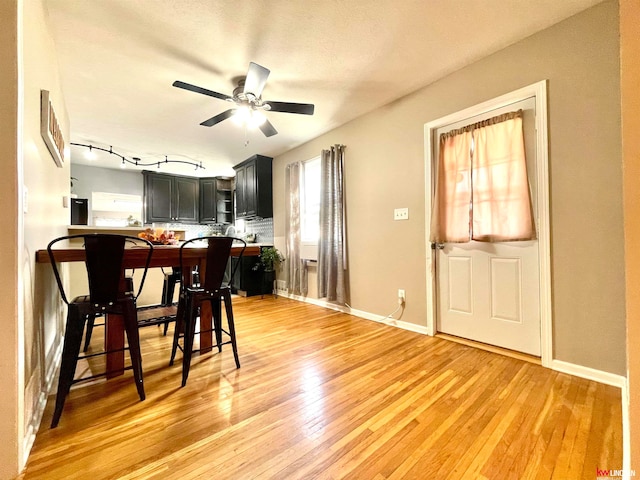 dining space featuring a textured ceiling, rail lighting, hardwood / wood-style floors, and ceiling fan