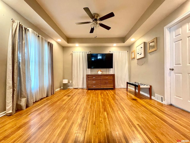 unfurnished living room featuring light hardwood / wood-style flooring, a tray ceiling, and ceiling fan