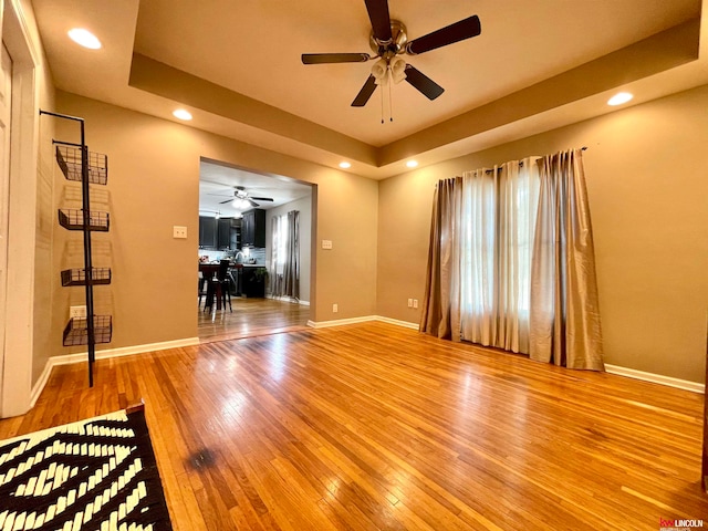 interior space featuring ceiling fan, hardwood / wood-style flooring, and a tray ceiling