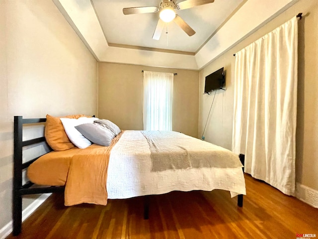 bedroom featuring a raised ceiling, hardwood / wood-style floors, and ceiling fan