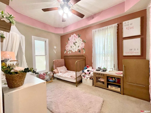 living area featuring ceiling fan, a raised ceiling, and light carpet