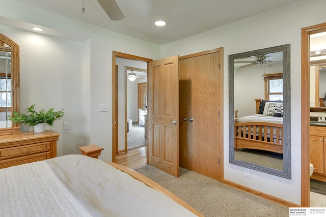 bedroom with connected bathroom, light carpet, and ceiling fan