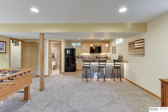 interior space featuring pendant lighting, a kitchen breakfast bar, black refrigerator, and light carpet