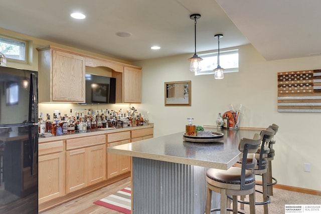 kitchen featuring light brown cabinetry, pendant lighting, and a wealth of natural light