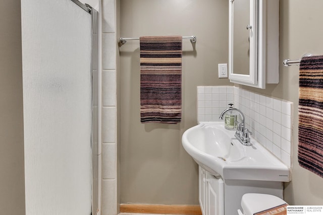 bathroom with decorative backsplash, toilet, and an enclosed shower