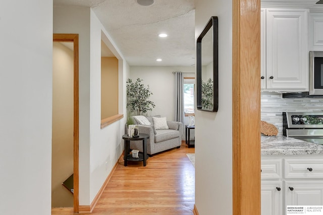 corridor with a textured ceiling and light wood-type flooring