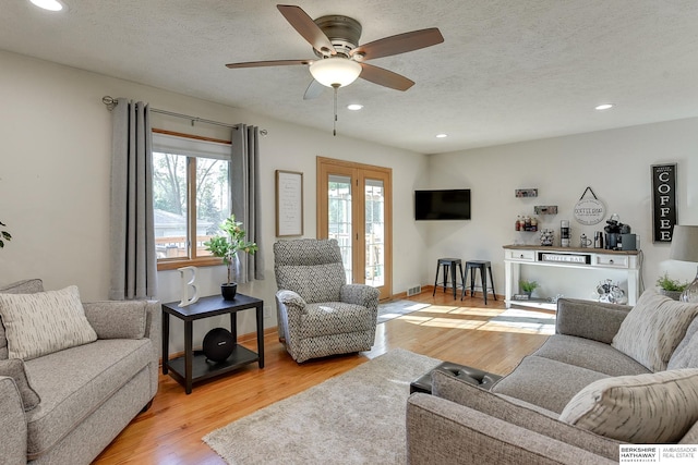 living room featuring ceiling fan, hardwood / wood-style flooring, and a textured ceiling